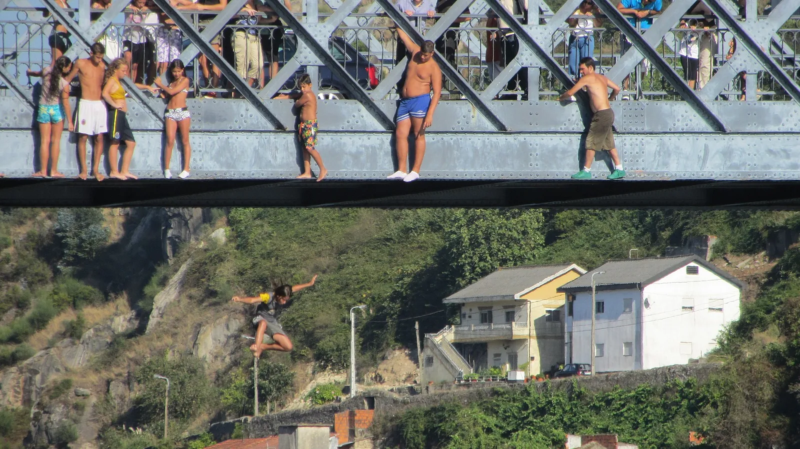 Kid jumping into river off of bridge Porto Portugal photograph